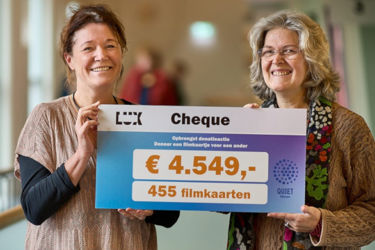 Brigitte neemt een cheque van Lux voor 455 kaartjes in ontvangst.