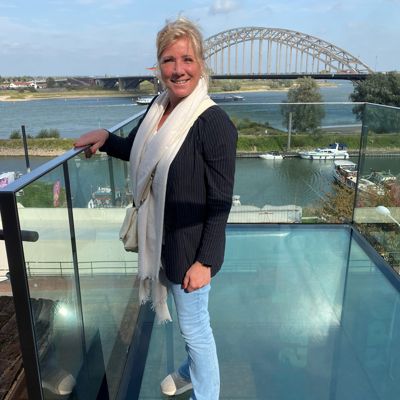 Nicolette staat op het uitkijkpunt op de Bastei. Ze draagt een gestreepte blazer en een witte sjaal. Op de achtergrond is de Waal te zien.